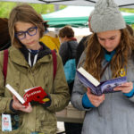Photo of two teenagers looking at open books. 