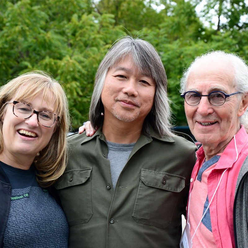 Photo of three people standing together and smiling at the camera.